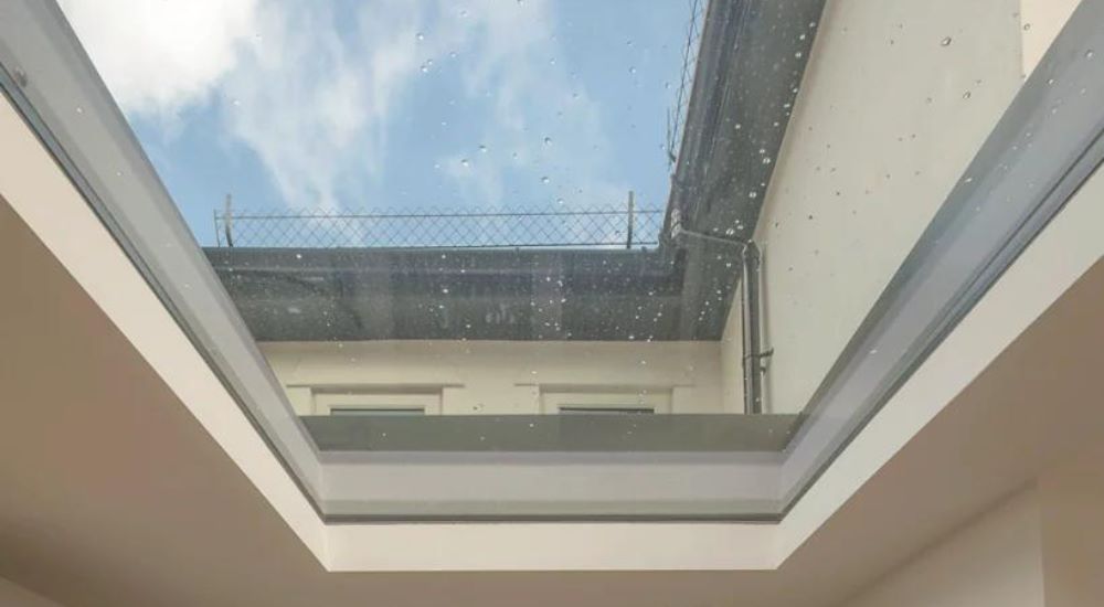 close up photo of rooflight, a cream building and fence can be seen through the glass