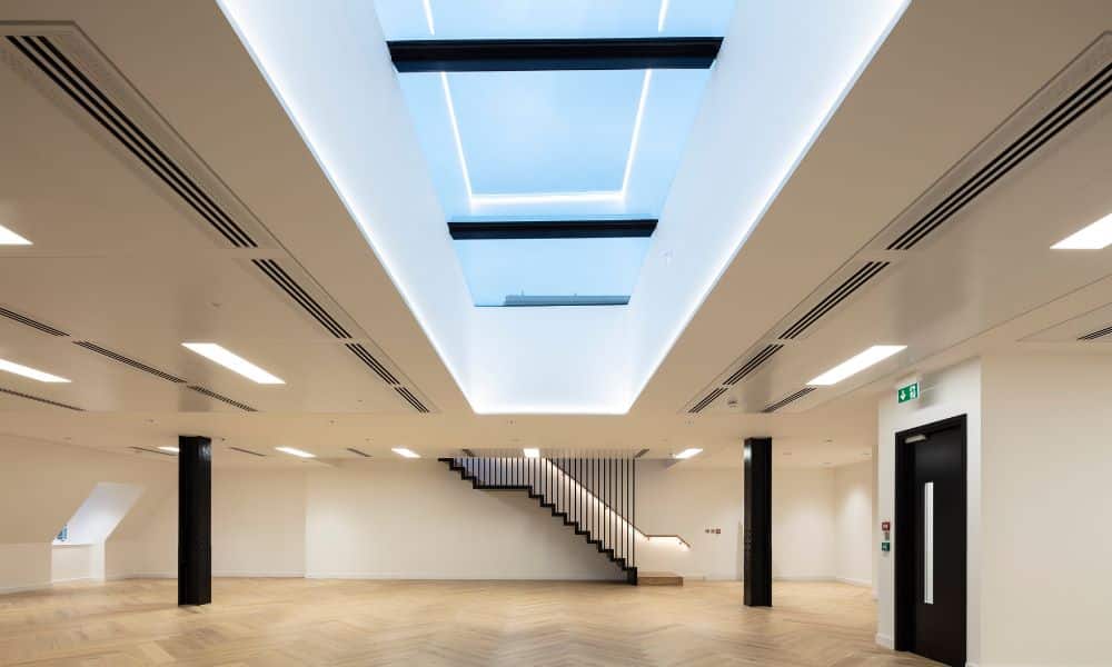 Large multipart rooflight in the ceiling surrounded by lighting and a black staircase at the back