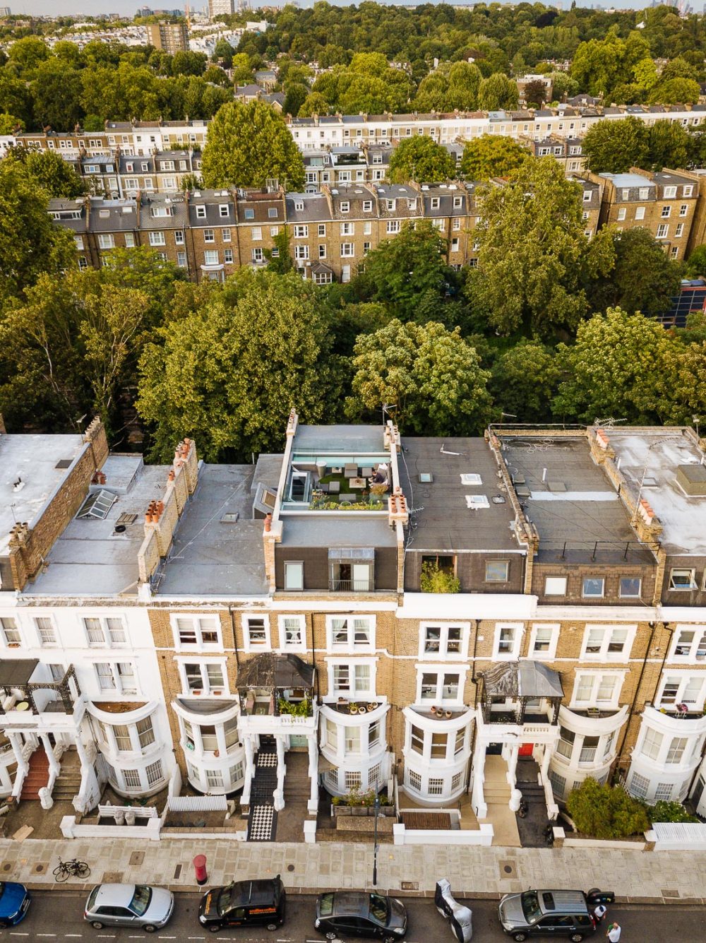 drone photograph of a terraced house rooftop, to the back is green trees and more terraced houses