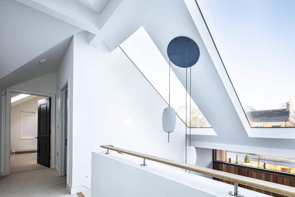 hanging lights hang in front of two large roof windows installed above the front door, a bedroom leads off to the left