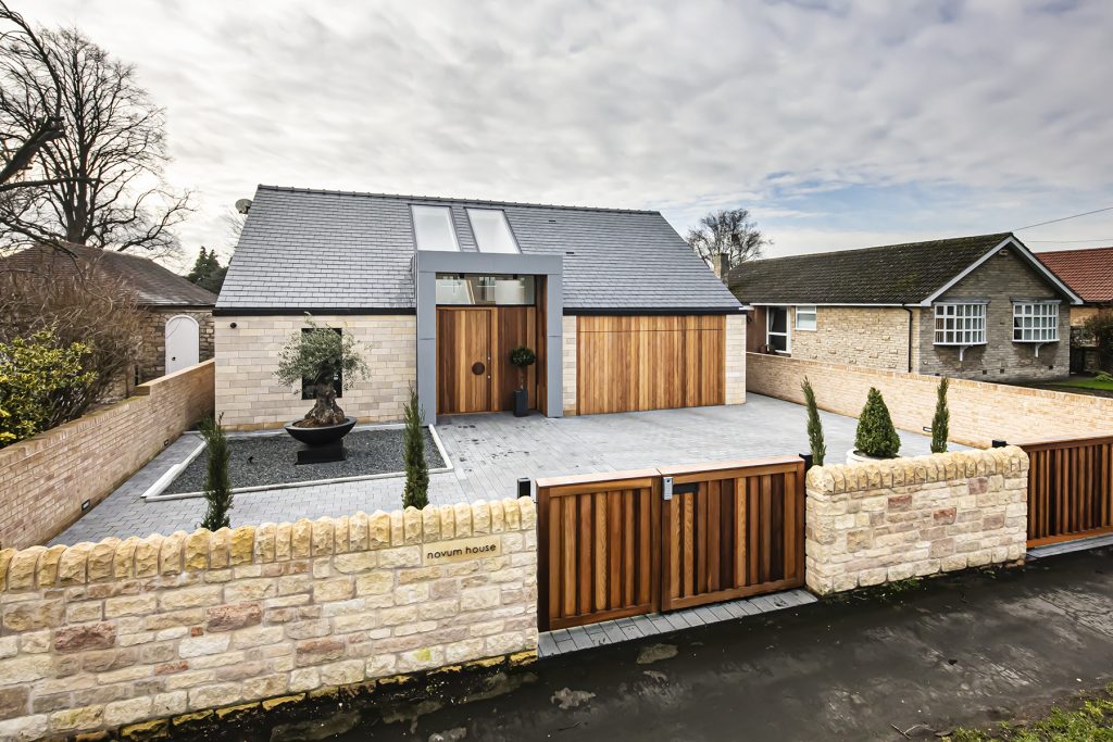 photo of a modern building with a tiled driveway and gate, two roof windows are the focus point5 of the house