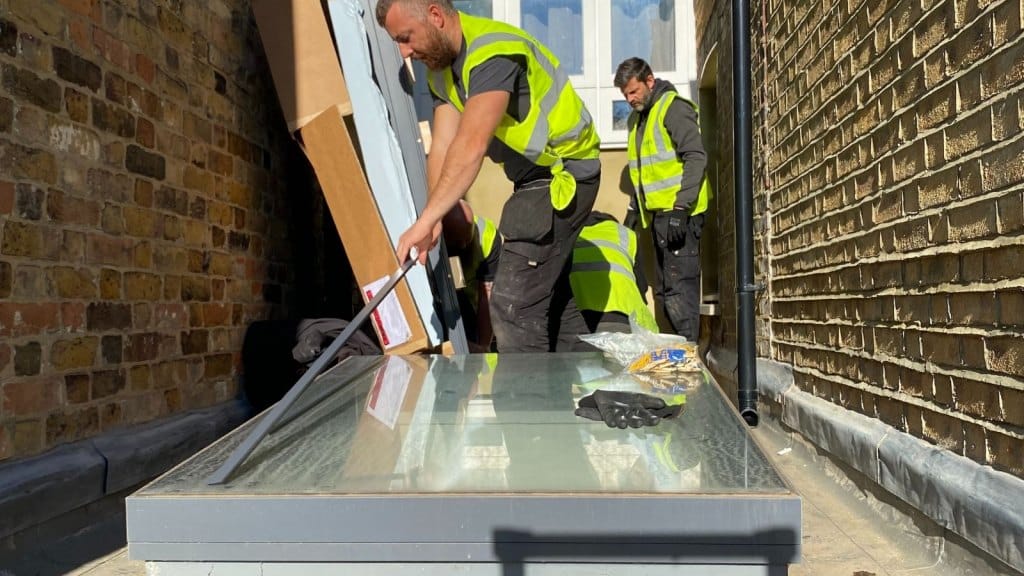 men in hi-viz jackets and work wear installing a Flushglaze rooflight on a flat rooftop