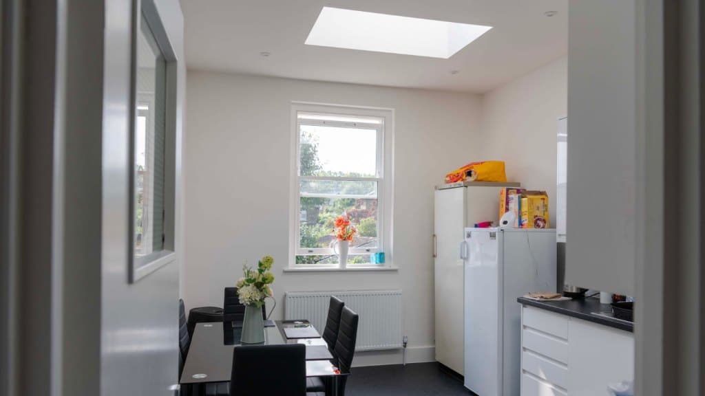 Communal kitchen in office space with a modern black set of table and chairs, rooflight installed