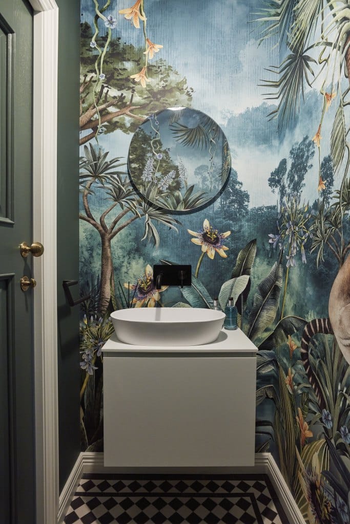 Jungle print wall paper in bathroom. Sink and checked floor also in image.